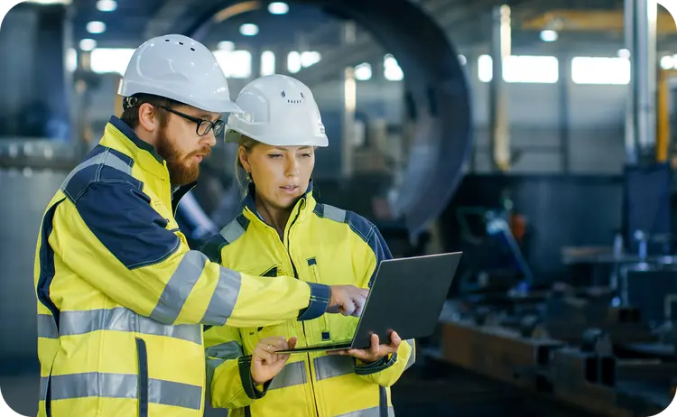 Two engineers reviewing workforce data on a laptop
